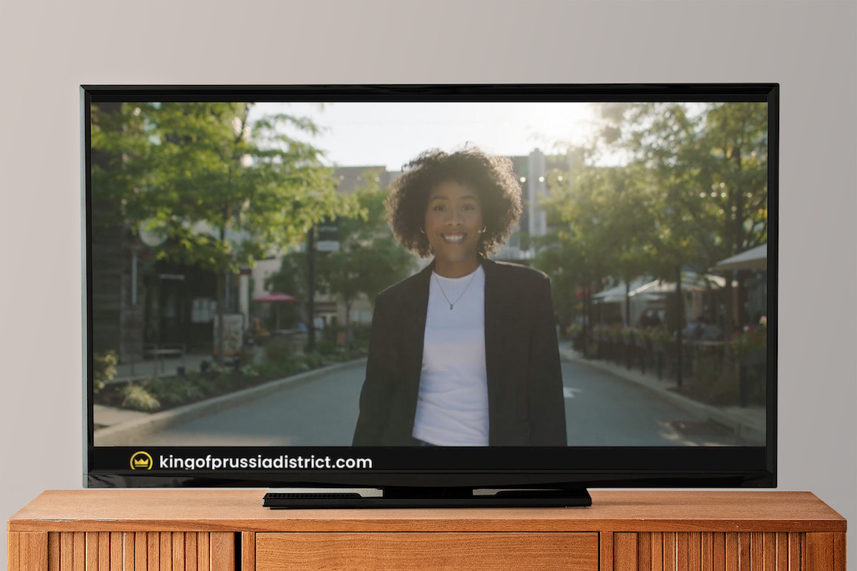 television showing an image of a woman on a street in a white shirt and black blazer, smiling