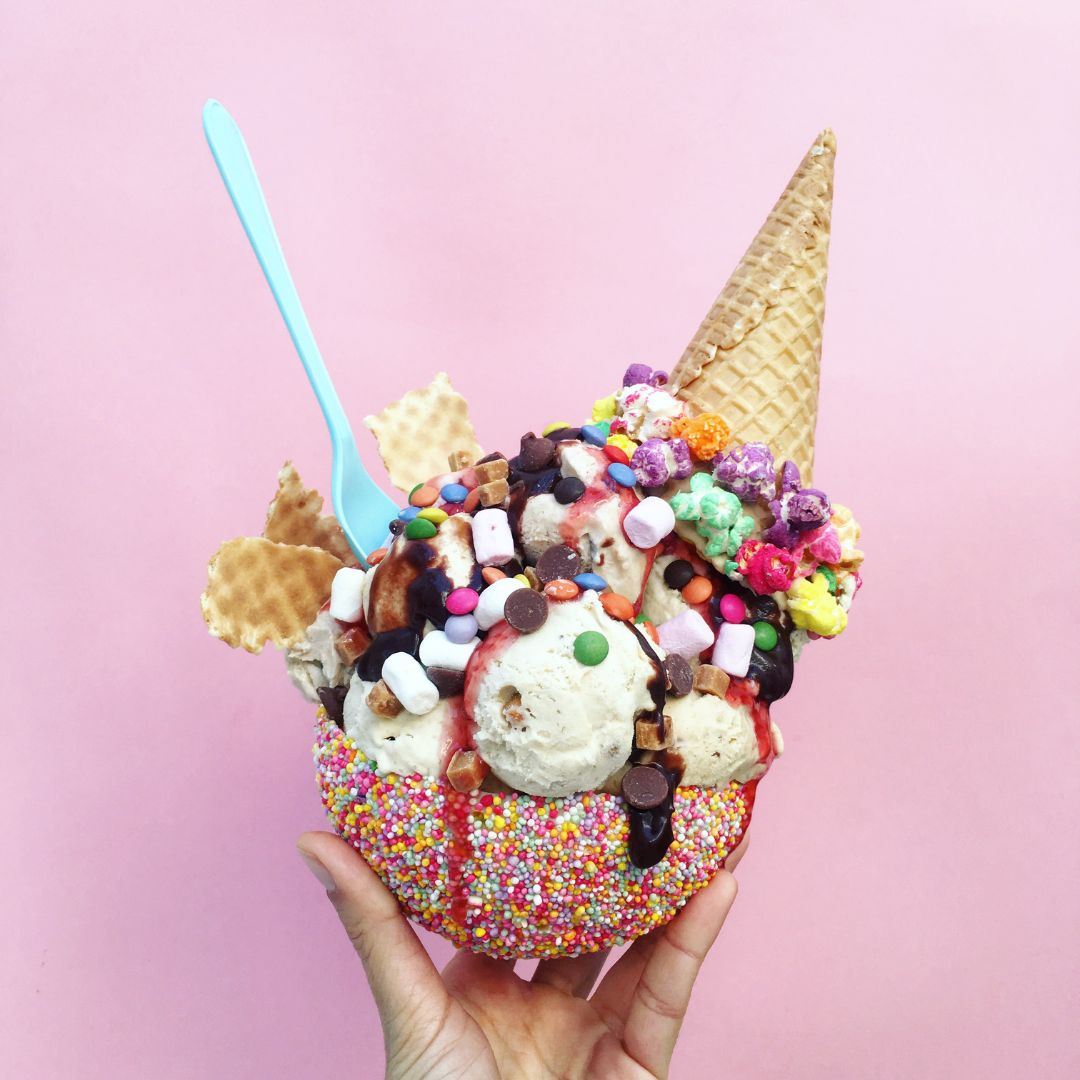 ice cream in a colorful bowl with a cone on top and lots of toppings