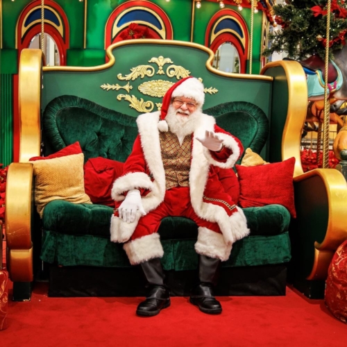 santa sitting on a green chair and smiling