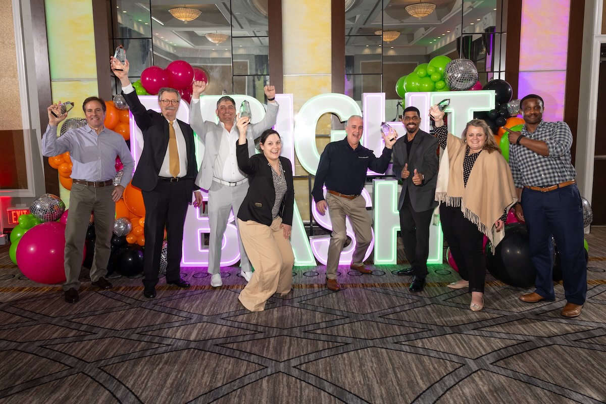 group of people in front of large marquee letters holding awards