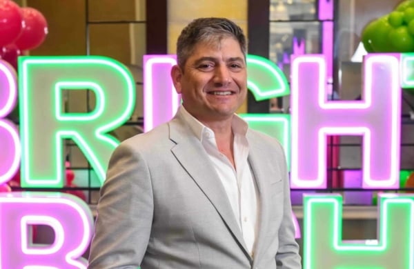 eric goldstein standing in front of neon lettering