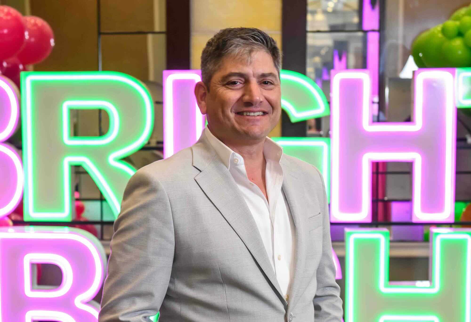 eric goldstein standing in front of neon lettering