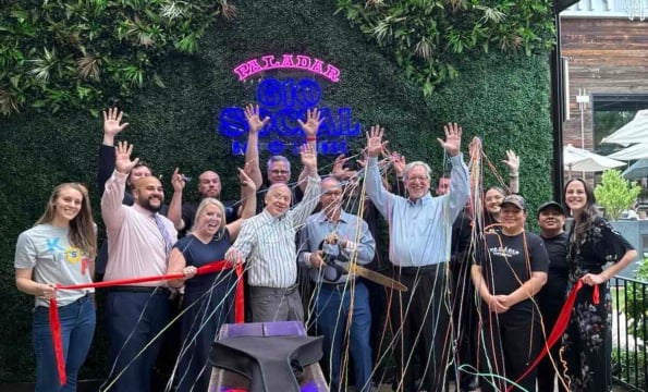 group of people standing in front of a green wall with a ribbon