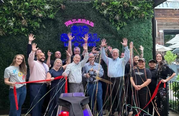 group of people standing in front of a green wall with a ribbon