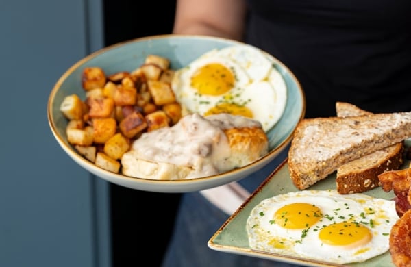 person holding bbreakfast plates