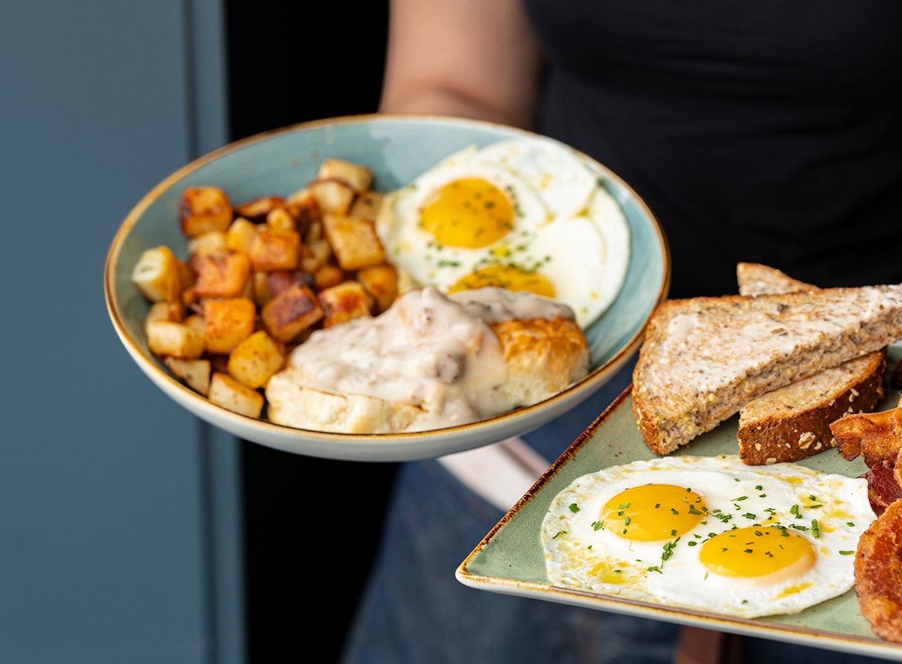 person holding bbreakfast plates