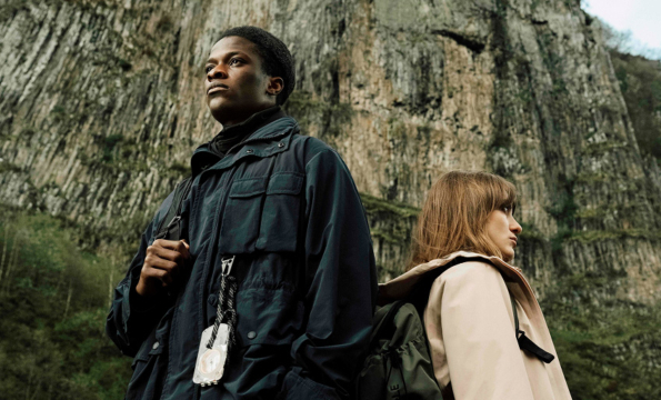people wearing coats standing in front of a mountain wall