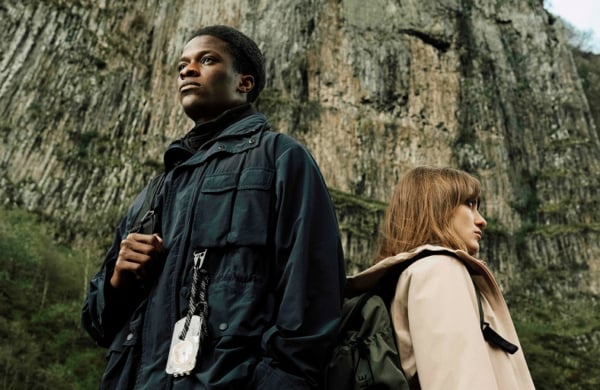 people wearing coats standing in front of a mountain wall