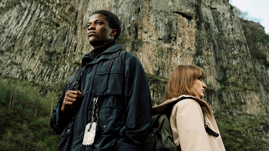 people wearing coats standing in front of a mountain wall