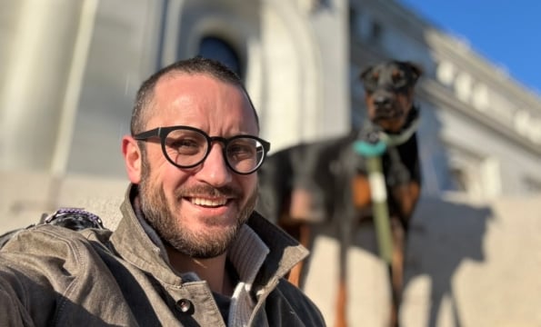 man sitting on steps outdoors with dog in background