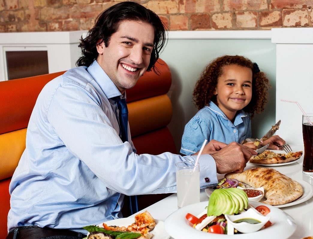 man helping young girl cut her food