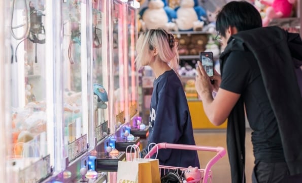 person standing outside of a gatchapon while another person takes a cellphone photo