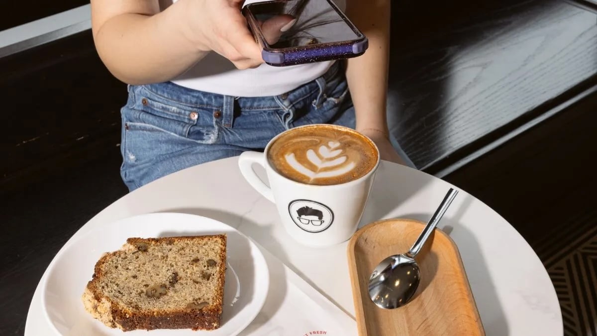 cellphone taking photo of coffee mug and breakfast dish