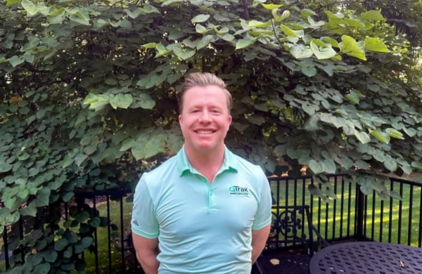 photo of man outdoors in front of large shrubbery