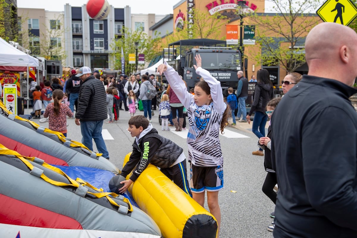 child playing basketball with block party crowd in background