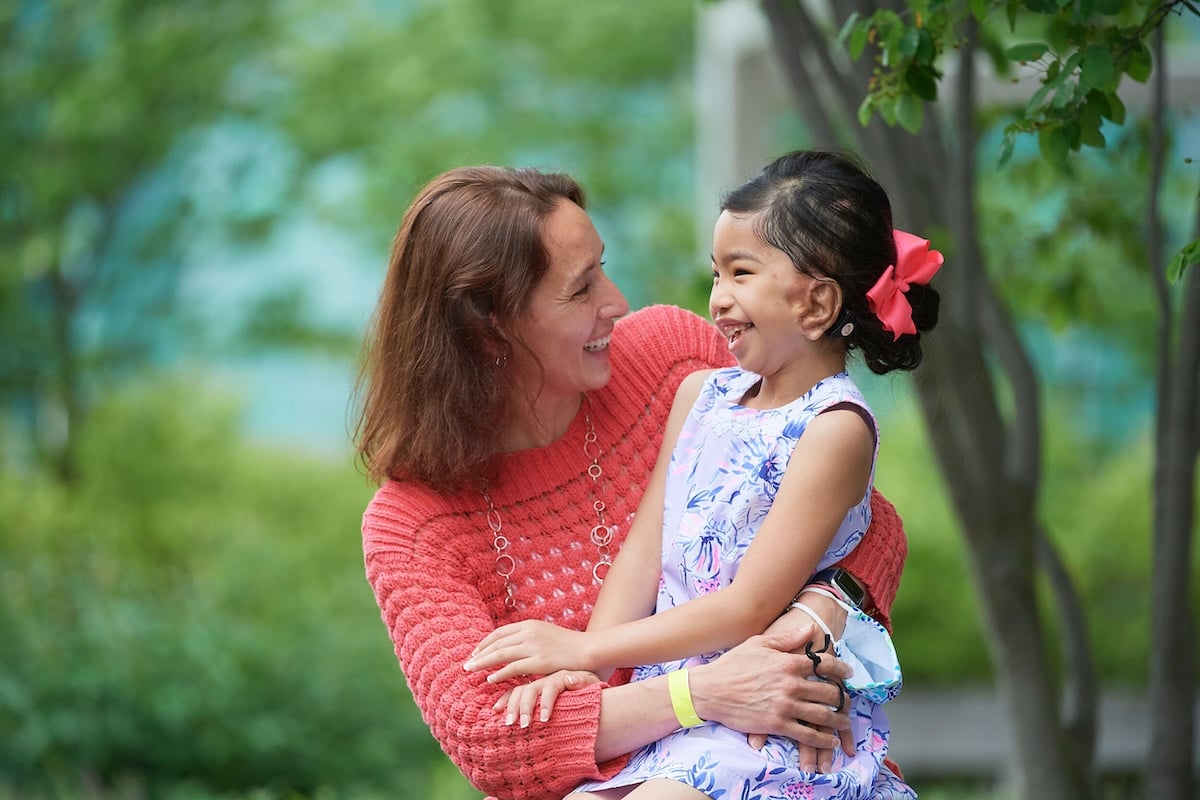 child and woman looking at each other and smiling, outdoors