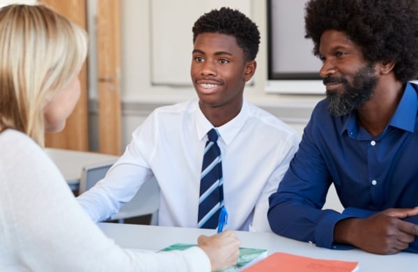 two men facing another person in an office setting