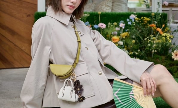 person wearing cross body bag and jacket outdoors with aa green fan spread out