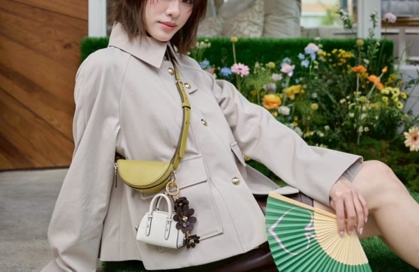 person wearing cross body bag and jacket outdoors with aa green fan spread out