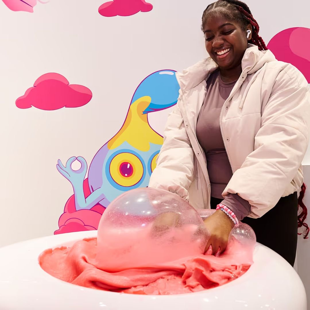 person with thier hands in a pink tub of slime