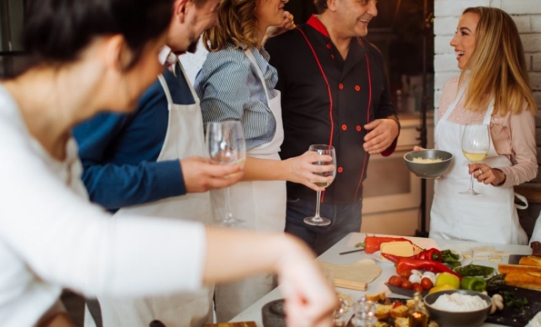 a bunch of people wearing aprons standing around a counter with food on it