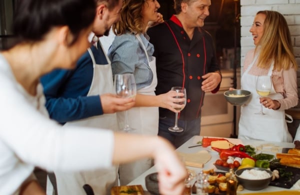 a bunch of people wearing aprons standing around a counter with food on it