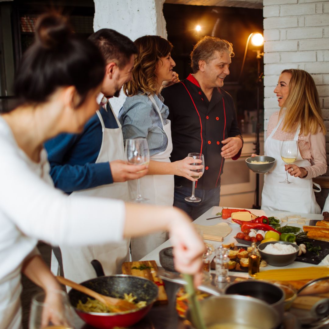 a bunch of people wearing aprons standing around a counter with food on it