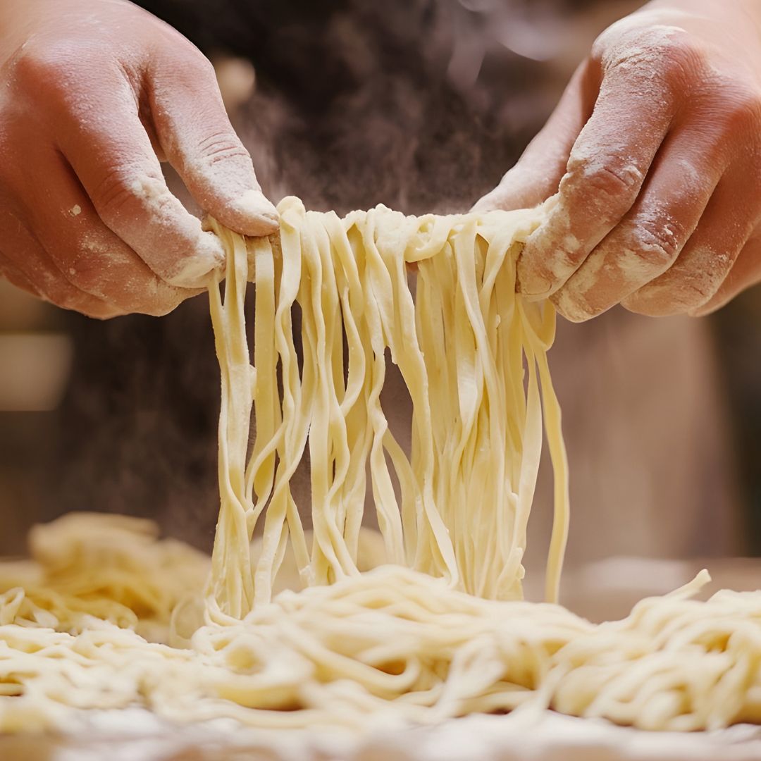 a hand holding pasta covered in flour
