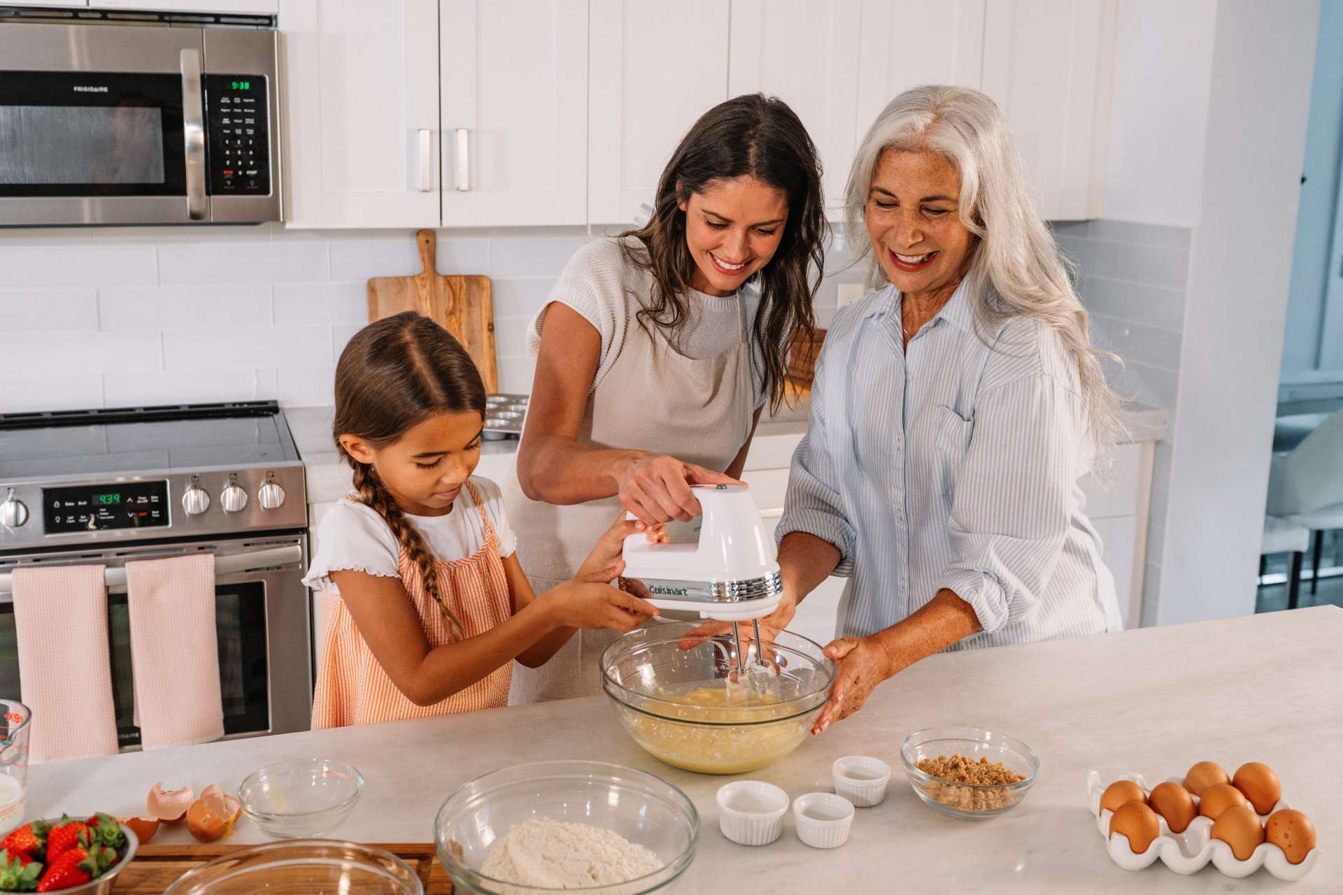 two womena nd a little girl mixing something in a bowl