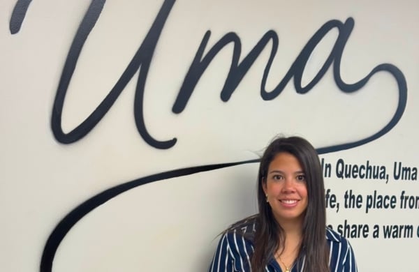 woman standing below a sign that says "Uma"