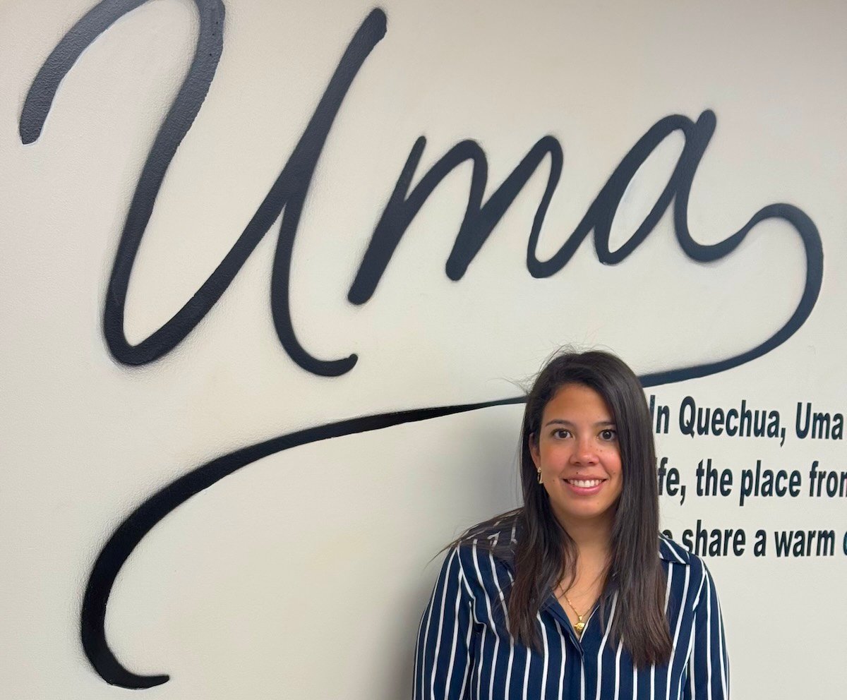 woman standing below a sign that says "Uma"