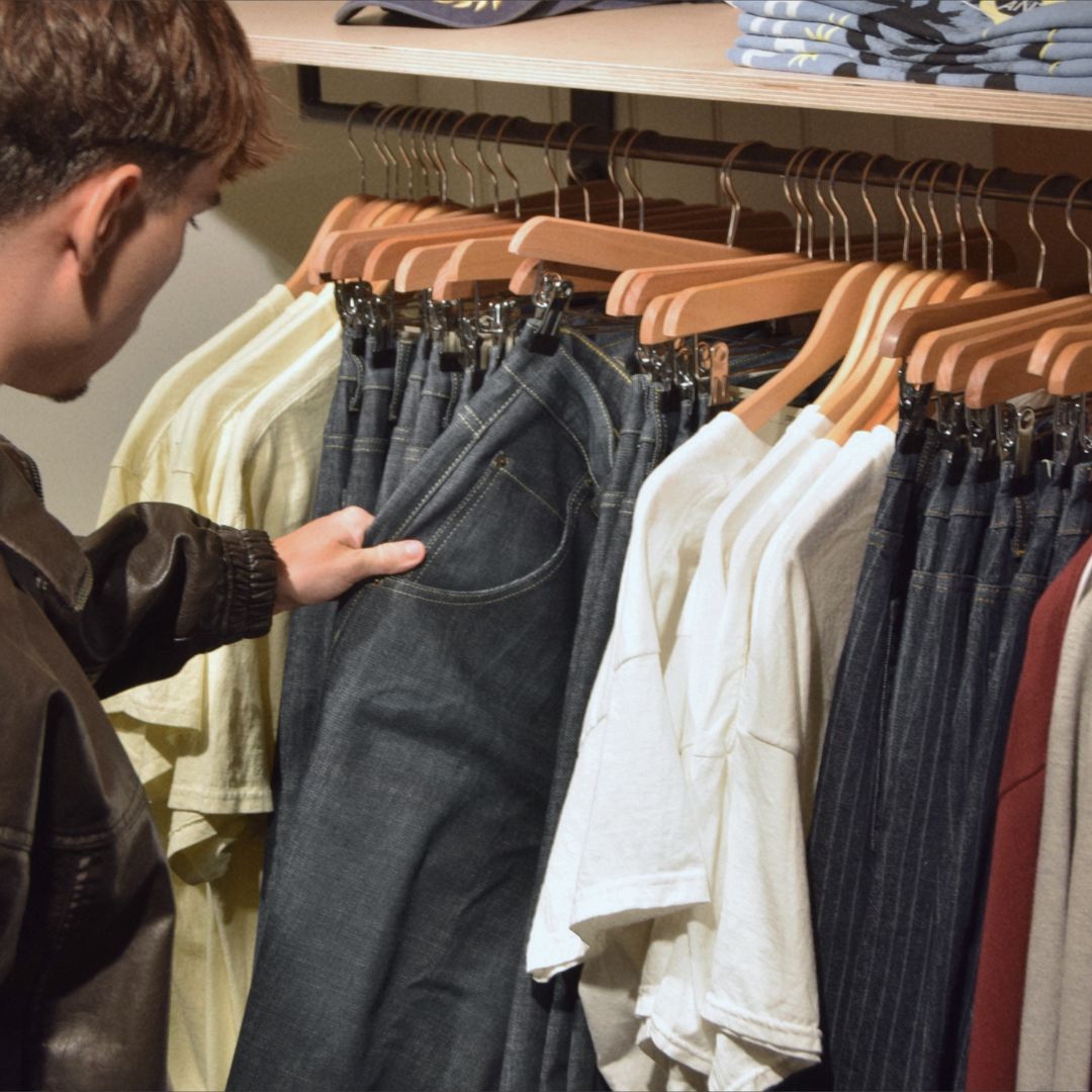a person pushing aside clothes on a rack
