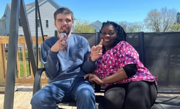 two people sitting on an outdoor swing and smiling