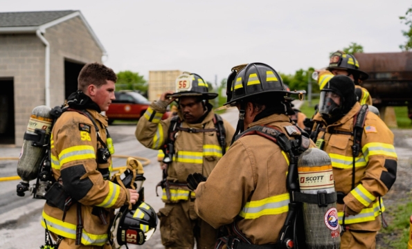 group of firefighters in their full gear in a huddle outside