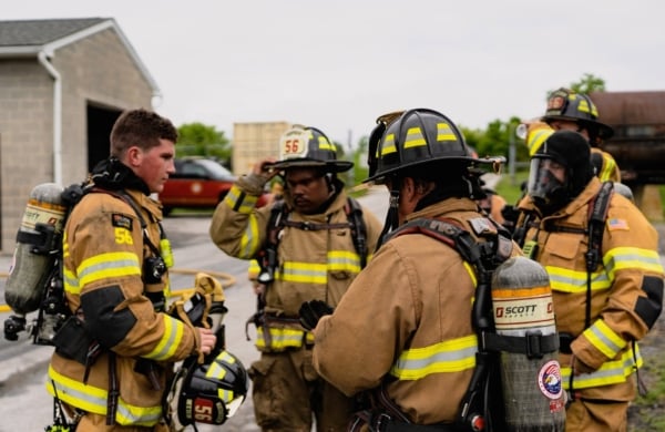 group of firefighters in their full gear in a huddle outside