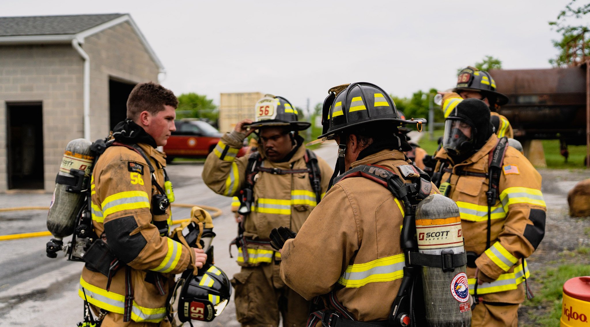 group of firefighters in their full gear in a huddle outside